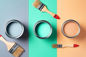 Metal paint cans and paint brushes on multicolor background. Top view. Copy space. Trendy green...