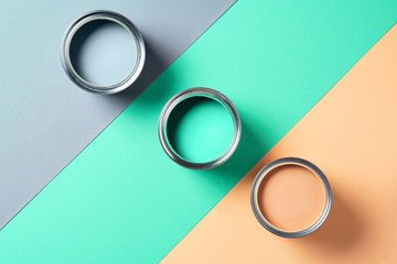 Open cans of paint on bright multicolored background. Top view. Copy space. Trendy green color...
