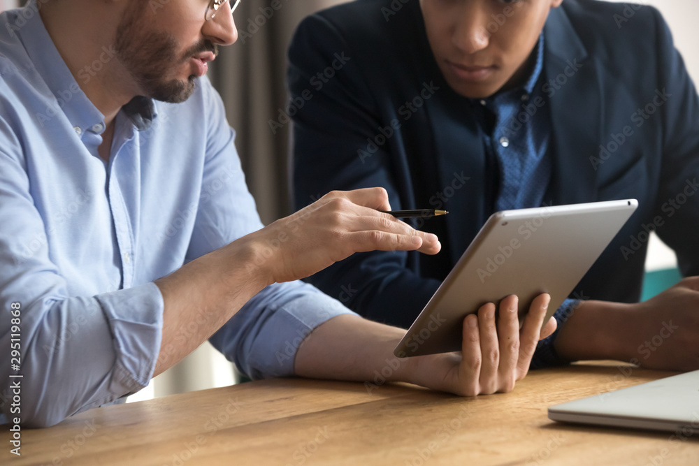 Poster diverse businessmen talking using digital tablet sit at desk, closeup