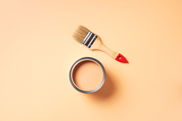 Paint brush and open paint can with on pastel background. Top view, copy space. Appartment renovation, repair, building and home design concept.