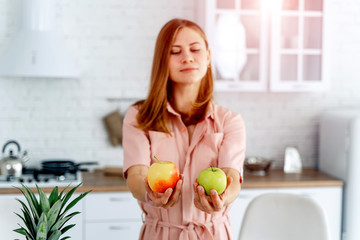Woman in kitchen ready to prepare meal with vegetables and fruits. Woman is holding apples.Kitchen...