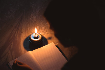 A student writing on notebook in a kerosene oil lamp 