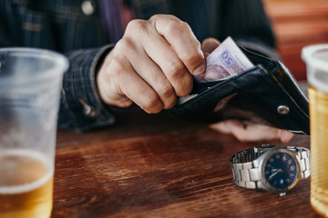 Hands get money from the wallet. Near glass of beer