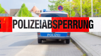 Polizeiabsperrung mit Polizeiwagen im Hintergrund