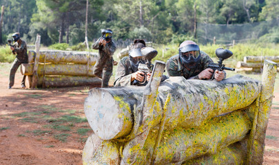 Portrait of team of adult people playing on paintball battlefield outdoor