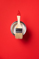 Brush and open paint can on trendy red background. Top view, copy space. Appartment renovation,...