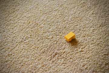 Childs yellow plastic building block on a carpet