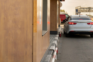Car near the window of a fast food restaurant. Payment and receipt of ready meals from the car. Fast food, car service.