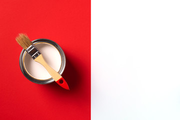 Wooden paint brush, open paint can on trendy red and white background. Top view, copy space. Appartment renovation, repair, building and home design concept.