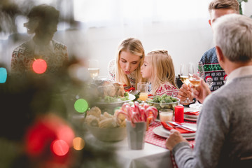 selective focus of family members sitting at table and celebrating Christmas