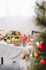 selective focus of plate with tasty turkey, corn, sweets and wine glasses on table in christmas