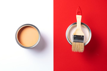 Wooden paint brush, open paint cans on trendy red and white background. Top view, copy space. Appartment renovation, repair, building and home design concept.