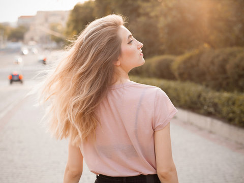 Young woman with long hair walking in the city. Back. Turn around.