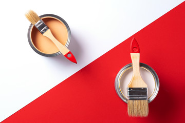 Wooden paint brushes, open paint cans on trendy red and white background. Top view, copy space....