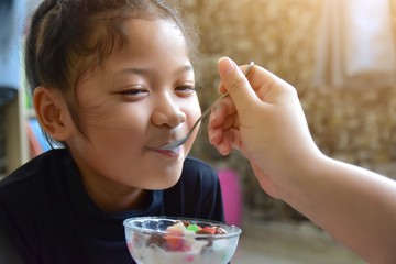 A cute little girl is eating deliciously and happy. Because his dearly beloved mother was feeding...