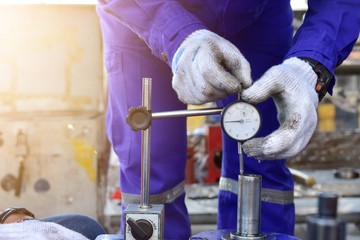 Technician measuring shaft endplay by Dial Gauge in the work shop.