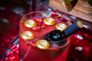 closeup of red wine bottle submerged in red liquid in big glass jar