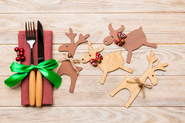 Top view of new year utensils on napkin with holiday decorations and reindeer on wooden background....