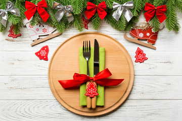 Top view of cutlery and plate on festive wooden background. New Year family dinner concept. Fir tree and Christmas decorations