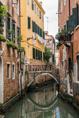 Fototapeta na wymiar Reflection of the bridge in the narrow Venetian canal