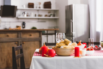 table with corn, glasses, candles and pumpkins in Thanksgiving day
