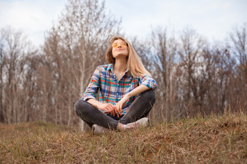 Happy young woman sitting on the hill in autumn.