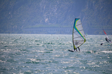 Windsurfer at Lake Garda glistening in the sun  with the street tunnels in the distance (Torbole, Italy)