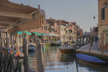 Murano island, Venice, cafeterias, canal, boats and street spree. Beautiful setting sun