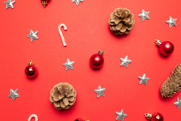 Top view of red background with pine cones, Christmas decoration silver stars, candy canes on red background.