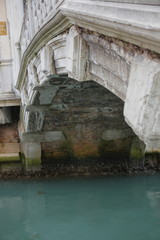 Bottom of the Marble Bridge, Venice, and the Grand Canal. Below the bridge is overgrown with green moss.