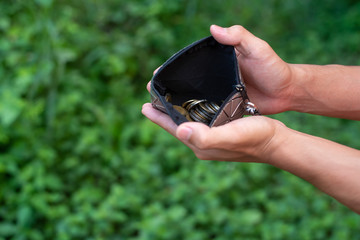 Men's hands have Thai coins. In the bag and there is a natural green scene about saving money