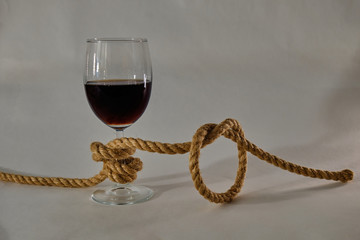 A glass of wine tied in a knot with a jute rope. Alcohol addiction