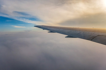 Obraz premium wing of airplane flying above clouds