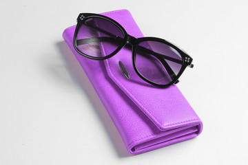 Purple leather wallet, sunglasses closeup on white background