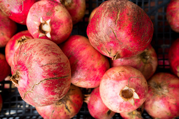 close up of red ripe pomegranates in a basket during autumn harvest, whole fresh and organic food for a healthy diet