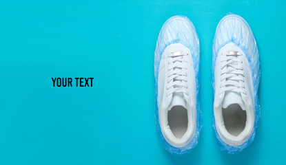 White sneakers in boot covers on blue background. Top view. Minimalism. Copy space