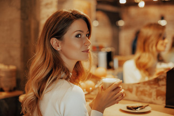 Young woman in cafe, girl drinks her favorite latte coffee