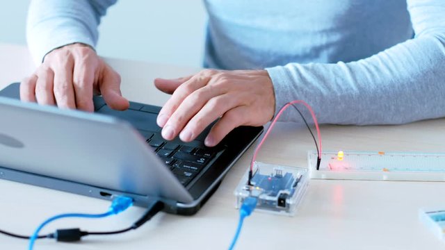 Automation technology. Smart home. QA engineer testing hardware with microcontroller.