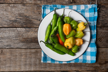 Raw serrano and habanero peppers on wooden background