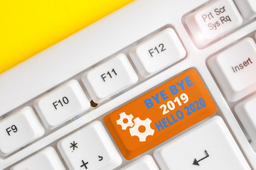 Handwriting text writing Bye Bye 2019 Hello 2020. Conceptual photo Starting new year Motivational message 2019 is over White pc keyboard with empty note paper above white background key copy space © A