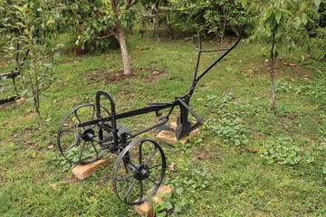 An old metal plow stands in the garden.