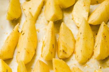 Delicious baked potatoes with rosemary on parchment, closeup. Vegetarian food. Potato country style