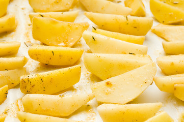 Delicious baked potatoes with rosemary on parchment, closeup. Vegetarian food. Potato country style
