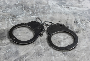 Steel handcuffs on gray concrete background. Crime, corruption concept