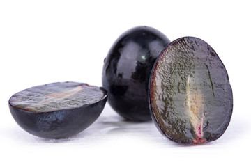 several dark grapes close up on a white background