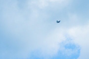 Fototapeta na wymiar green airplane flying high in a cloudy blue sky. long-range shooting