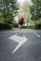 Young female athlete running fast at urban suburbs street road on autumn.