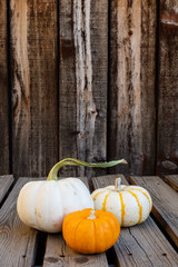 Three small fall gourds on a rustic plank table with room for copy