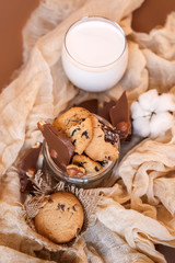 Obraz na płótnie Canvas Shortbread chocolate cookies and a glass of milk on a brown background. Milk chocolate with nuts and cookies.