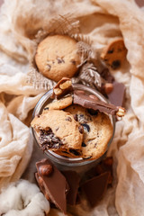 Shortbread chocolate cookies and a glass of milk on a brown background.  Milk chocolate with nuts and cookies.